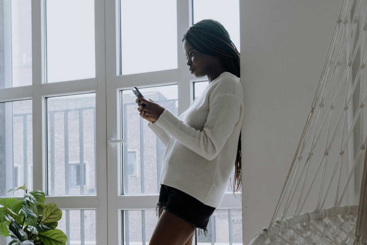 Una ragazza con un maglione bianco che guarda un telefono