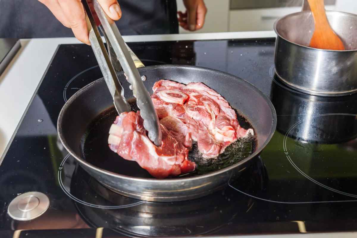 Persona che cuoce carne in una padella