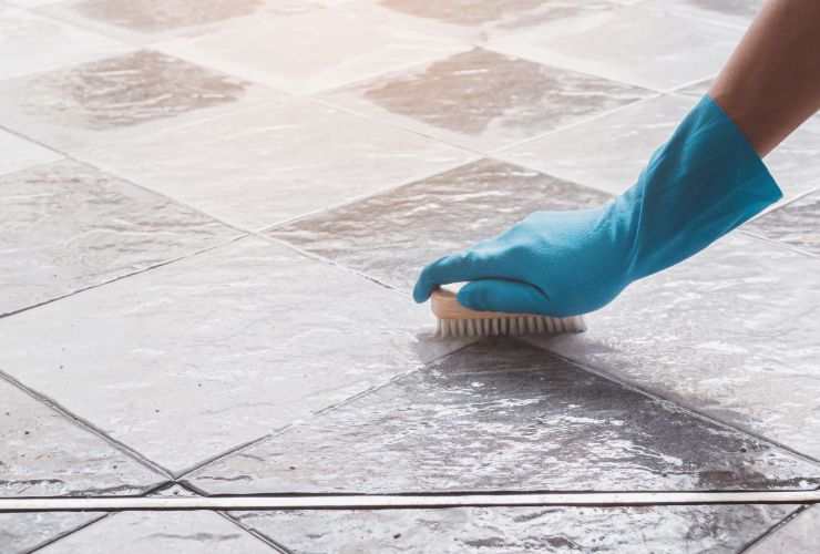 donna che pulisce fughe pavimento con spazzola