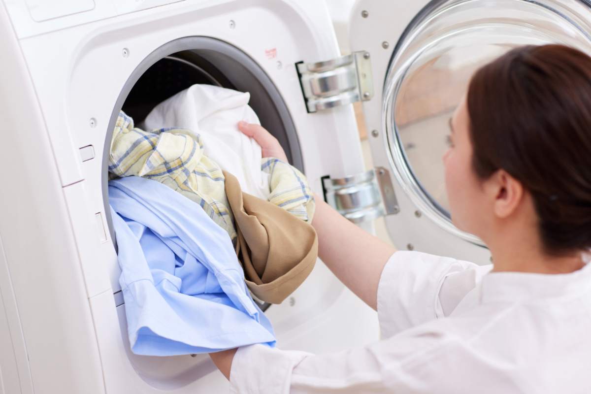 Donna che mette i panni nella lavatrice