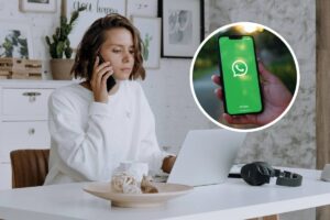 Una ragazza che parla al telefono al lavoro e, in evidenza, uno smartphone con WhatsApp