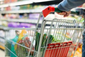 Persona che spinge carrello pieno in un supermercato