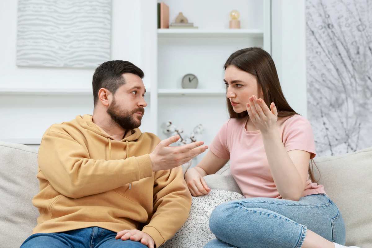 Un uomo e una donna che litigano seduti sul divano