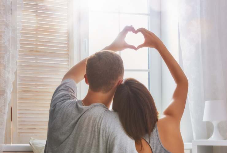 ragazzo e ragazza di spalle che formano un cuore con le mani