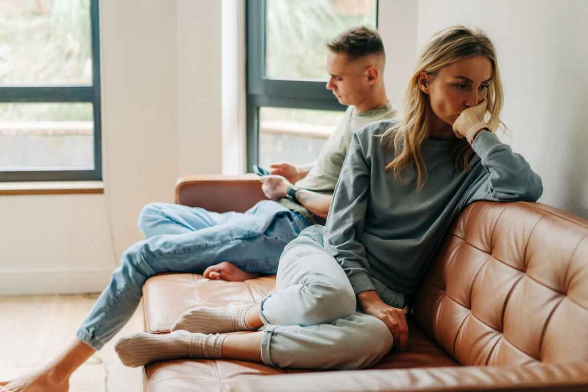 Un uomo e una donna seduti sul divano. Lei ha la testa di lato