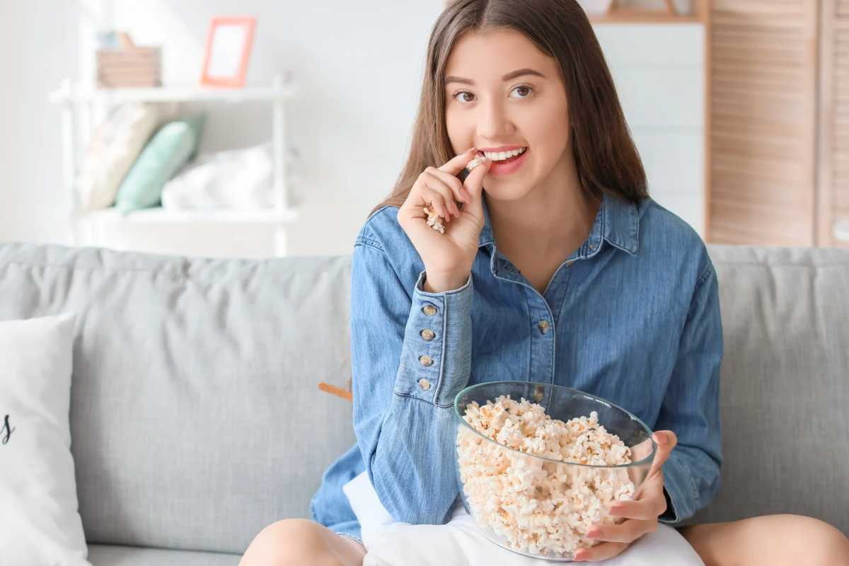 Donna che mangia popcorn sul divano