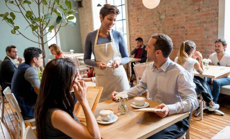 Persone sedute a tavola e donna in piedi